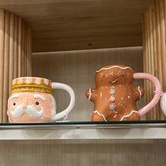 two coffee mugs are sitting on a shelf