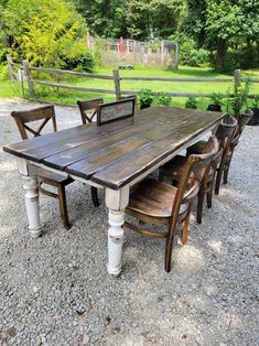 an outdoor table and chairs are set up on graveled area with trees in the background