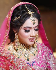 a woman in a pink and gold bridal outfit with jewelry on her head,