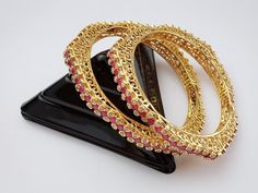 Designer Ruby gold plated bangles are studded with semiprecious stones. Polish and stones are guaranteed. Comes in a pair ( 2 bangles) Jewelry care instructions : 1. Keep jewelry away from direct heat,water,perfumes,deodorants and other strong chemicals. 2. Any moisture or sweat should be properly wiped off before preserving inside.Store it in air tight zip lock bags NOT in velvet box or pouch. Store it in cool, dry place. 3. Your jewelry should be the last thing you put on and the first thing to take off. Imitation jewelry is not meant to last forever, but why not to make it last, as long as you can Designer Bangles, Jewellery Wedding, Bracelets Design, Gold Plated Bangles, Bangles Indian, The Bangles, Jewelry Care Instructions, Indian Wedding Jewelry, Bangle Designs