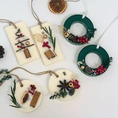 some ornaments are hanging from strings on a white table with pine cones and other decorations