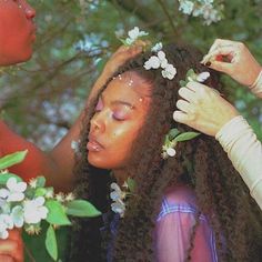 two women with flowers in their hair are looking at each other while one woman holds her head