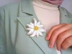 a close up of a person wearing a green shirt and a white flower brooch