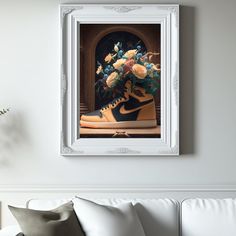 a painting of flowers in a pair of sneakers on a couch with a white frame