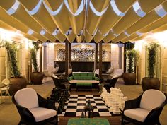 a living room filled with lots of furniture under a covered area next to a checkered floor