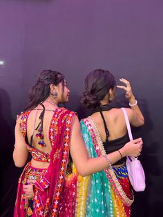 two women dressed in colorful sari standing next to each other