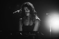 a woman sitting in front of a keyboard on top of a stage next to a microphone