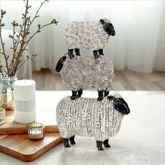 two black and white sheep standing on top of each other in front of a vase