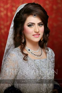 a woman in a wedding dress posing for the camera with her hair pulled back and wearing a tiara