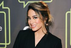 an image of a woman smiling at the camera with her hair in a bun and earrings on