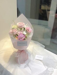 a bouquet of pink and white flowers sitting on top of a table