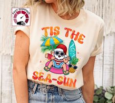 Tis the sea sun shirt,Christmas in july shirt,Tropical Christmas shirt,Santa in july shirt,Coastal christmas,Summer Christmas,Surfer Santa https://etsy.me/349fSXd PRODUCT DESCRIPTION Please check the colors and sizes on the images! .: Retail fit .: 100% Soft cotton (fibre content may vary for different colors) .: Light fabric (4.2 oz/yd² (142 g/m .: Tear away label .: Runs true to size Machine wash: warm (max 40C or 105F); Non-chlorine: bleach as needed; Tumble dry: low heat; Iron, steam or dry: Christmas Beach Shirts, Christmas Cruise Shirts Ideas, Beach Season Holiday Cotton T-shirt, Beach Holiday Cotton T-shirt, Beach Holiday Graphic Print T-shirt, Graphic Print T-shirt For Beach Holiday, Cotton T-shirt For Beach Holiday, Beach Season Holiday Beachwear Tops, Holiday Beach Season Beachwear Tops