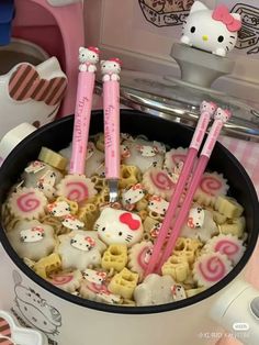 two hello kitty straws are in a cup with some food on the table next to it