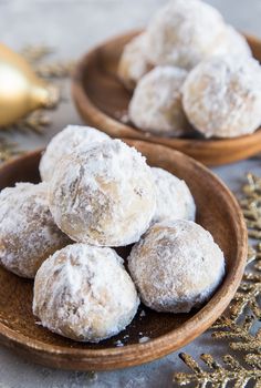 some powdered sugar balls are on a wooden plate next to a christmas ornament