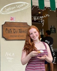 a woman with red hair is smiling and holding a donut in front of a cafe