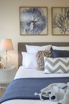 a bedroom with two paintings on the wall above the bed, and a blue comforter