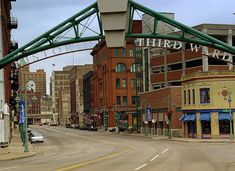 an empty city street with cars parked on the side and buildings in the back ground