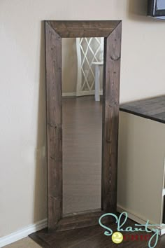 a mirror sitting on top of a wooden floor next to a cabinet and tv monitor