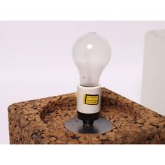 a light bulb sitting on top of a cork block with a black base and yellow label