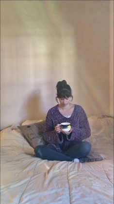 a woman sitting on top of a bed holding a bowl