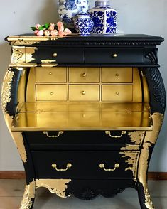 an ornate black and gold desk with vases on top