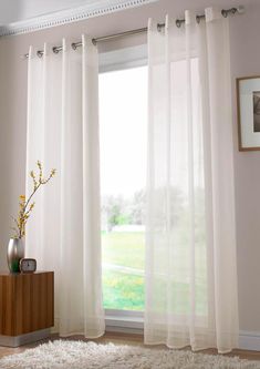 a living room with white curtains and a rug