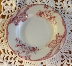 a white and red plate on a doily with crocheted lace around it