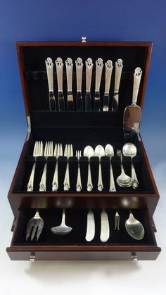 an assortment of silverware in a wooden case