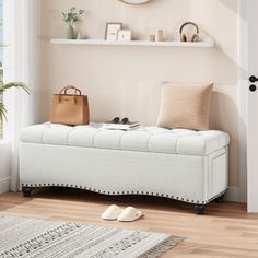 a white bench sitting in front of a window next to a rug and wall mounted clock