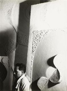 a man standing in front of a wall with sculptures on it's sides and shadows cast by the walls