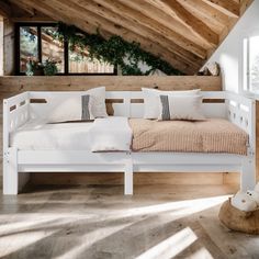 a white bed sitting in the middle of a room under a slanted wooden ceiling