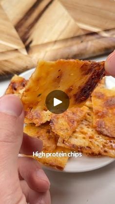 someone is holding up some food on a plate with the words high protein chips in front of them