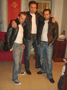 three men standing next to each other in a living room