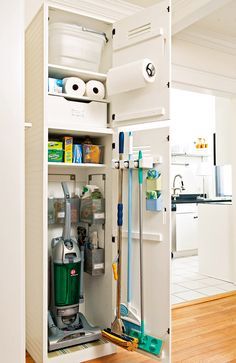 an open refrigerator with cleaning supplies and tools in it's door, next to a hardwood floor