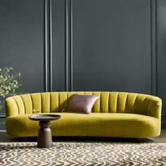 a living room with grey walls and a yellow couch in the middle, surrounded by rugs