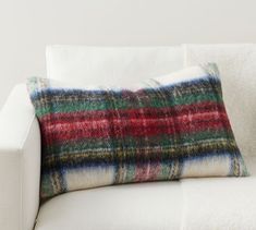 two plaid pillows sitting on top of a white couch next to each other in front of a wall