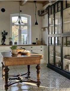 a kitchen with an old fashioned table in the center and lots of glass cabinets behind it