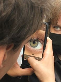 a woman wearing a face mask is looking at her cell phone with an eye on the screen