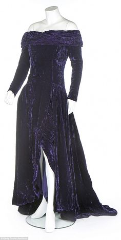 an off the shoulder purple velvet dress with long sleeves and high slits on display