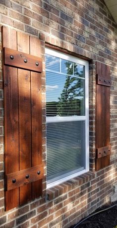 a brick building with two windows and shutters