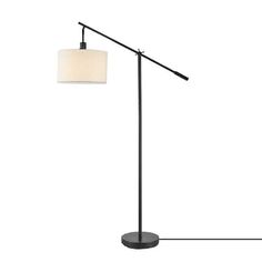 a black floor lamp with a white shade on the top and an oval light fixture at the bottom