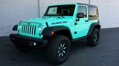 a blue jeep is parked in front of a white garage door with the word rubcion written on it