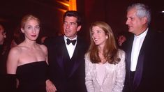 three people standing next to each other in formal wear and tuxedos at an event