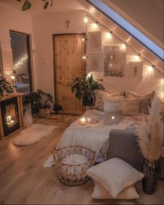 a bed with pillows, blankets and candles in a room that is decorated with lights