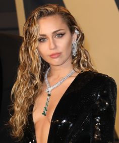 a woman with long curly hair wearing a black dress and diamond jewelry on her neck