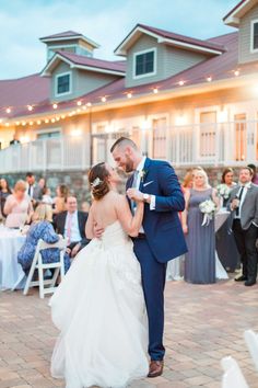 a bride and groom share their first dance at the reception in front of an outdoor venue