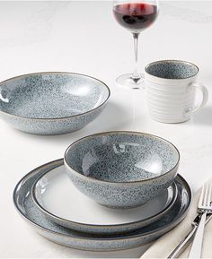 the table is set with two cups and three plates, one has a wine glass on it