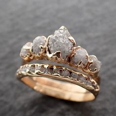 two gold rings with rough white diamonds on each one, set against a black background