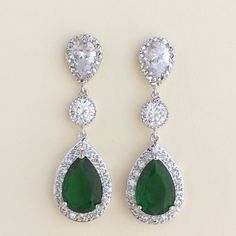 Luxury green emerald cubic zirconia bridal teardrop earrings in rhodium plated brass setting. Earrings feature a large teardrop with pear cut green emerald cubic zirconia center surrounded by tiny round zirconia crystals. Teardrop dangles from a clear cubic zirconia ear stud and a round cubic zirconia connector. Total length of the earring is 4.6 cms. Also available in clip on style. For matching necklace click: https://www.etsy.com/listing/481705468/green-emerald-cubic-zirconia-bridal?ref=listi Pear-shaped Emerald Earrings For Wedding, Green Cubic Zirconia Bridal Earrings, Teardrop Emerald Earrings For Wedding, Cubic Zirconia Teardrop Earrings For May Birthstone, Green Teardrop Cubic Zirconia Earrings, May Birthstone Teardrop Cubic Zirconia Earrings, Green Teardrop Bridal Earrings For Wedding, Green Teardrop Dangle Earrings For Wedding, Green Teardrop Wedding Earrings