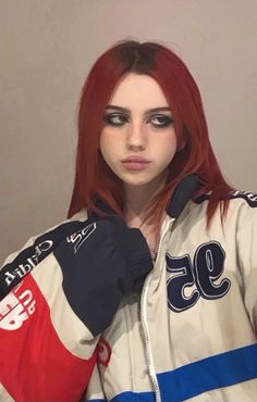 a woman with red hair and black eyeliners is wearing a jacket that has the number 95 on it